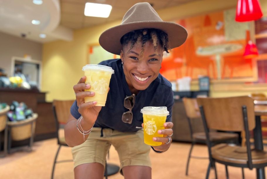 woman holding two Starbucks drinks