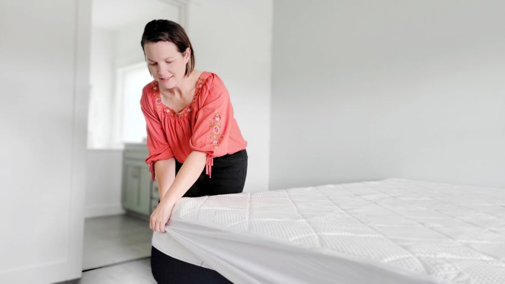 woman putting a Swiss Comforts Mattress Protector on a bed