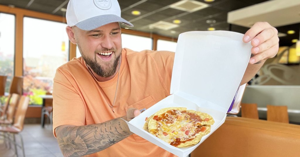 man holding up a taco bell mexican pizza