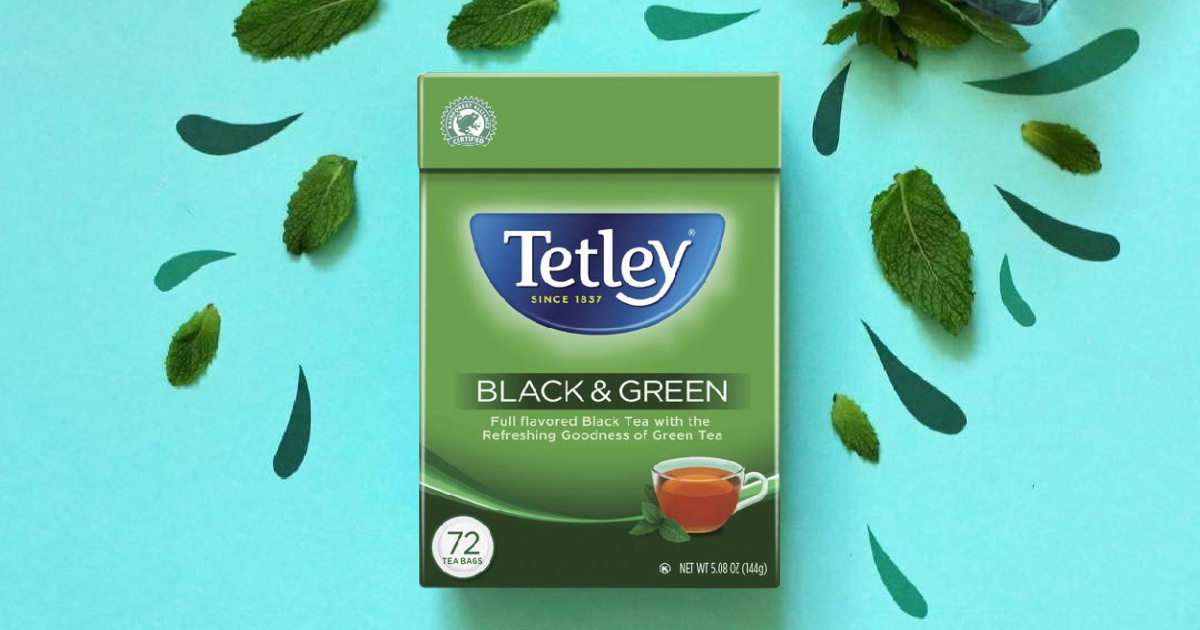 box of black and green Tetley tea and tea leaves against a mint green background