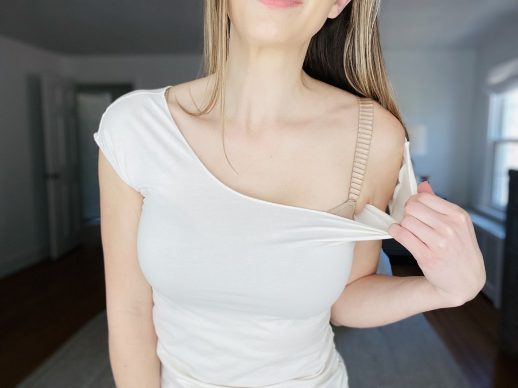 Woman showing glimpse of beige third love bra under white shirt