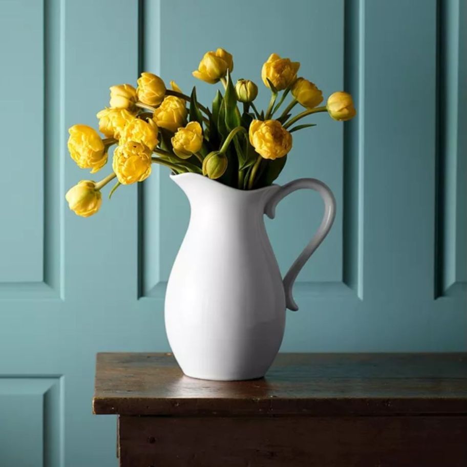 a white porcelain pitcher filled with yellow tulips