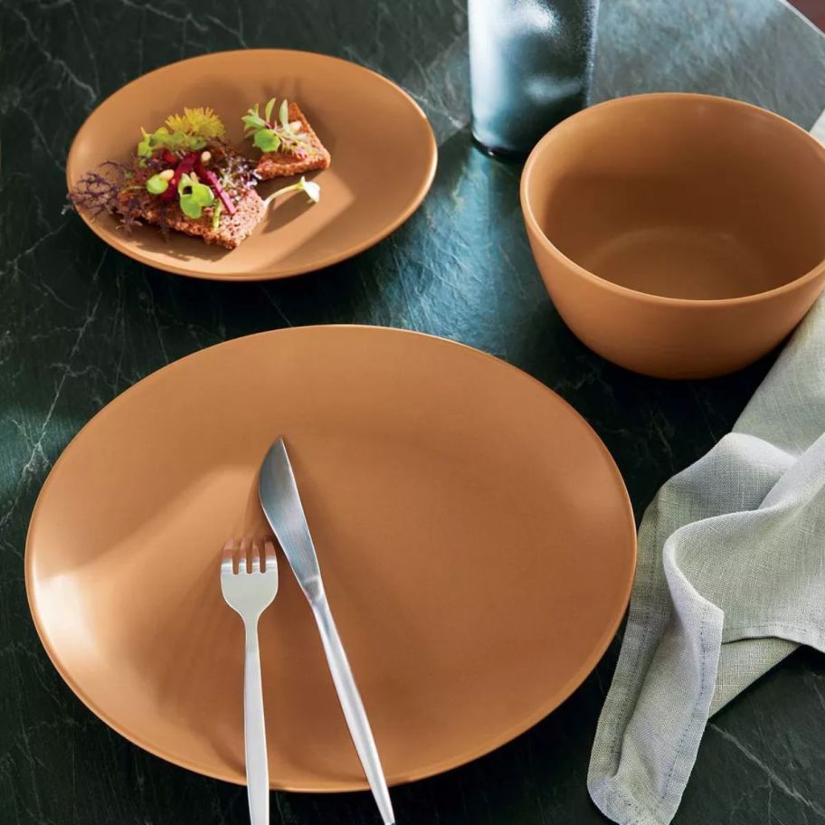 a 3 piece place setting in terracotta colored stoneware
