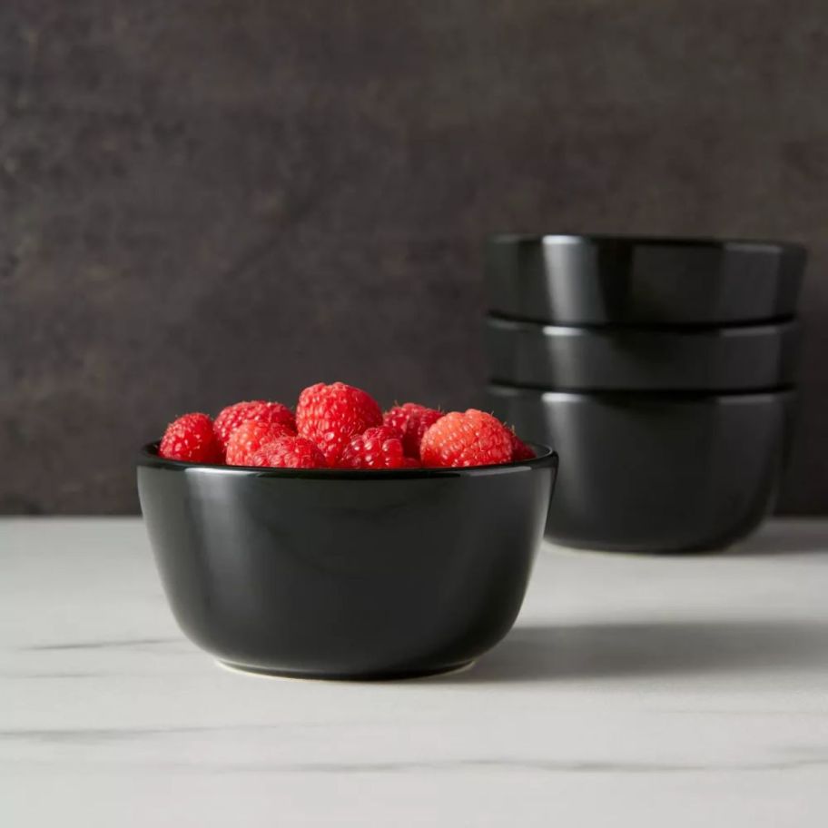a black stoneware bowl filled with fresh raspberries