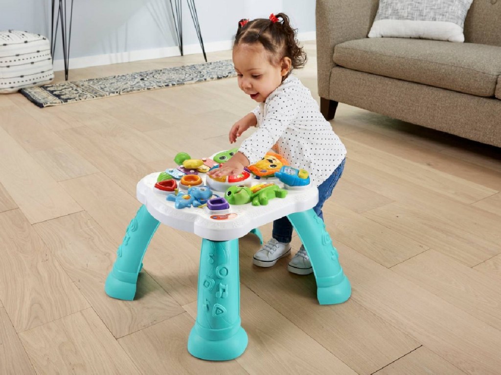 little girl playing with activity table in living room