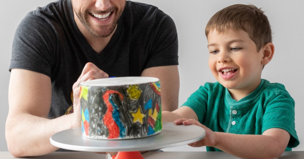 man and young boy decorating a cake
