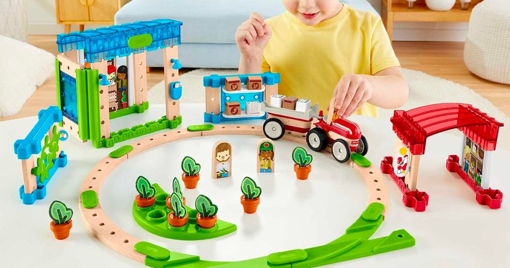 boy in yellow shirt playing with fisher price train set