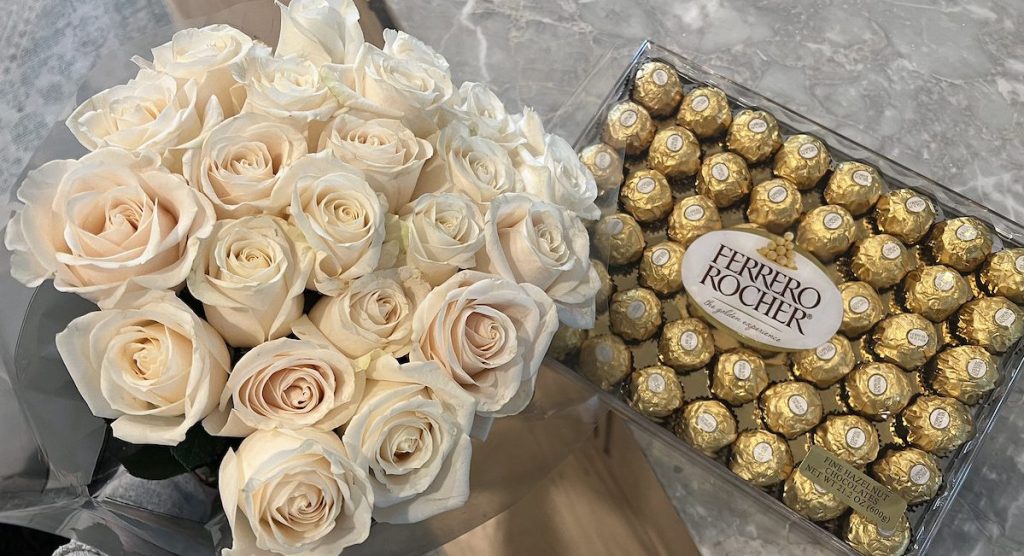 close up of white bouquet of roses with box of chocolates