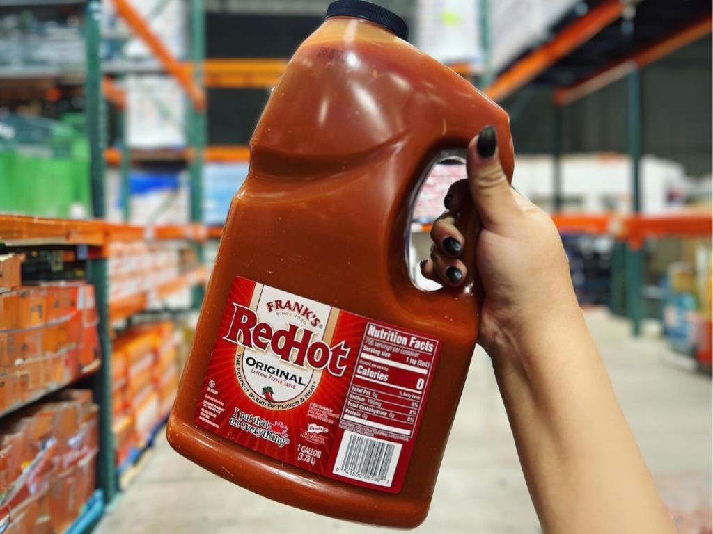 franks hot sauce gallon jug being held up by hand