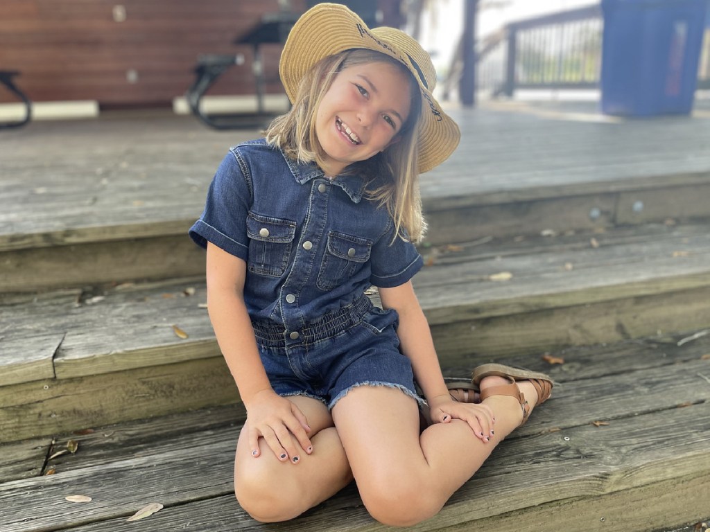 girl wearing jean jumpsuit and hat
