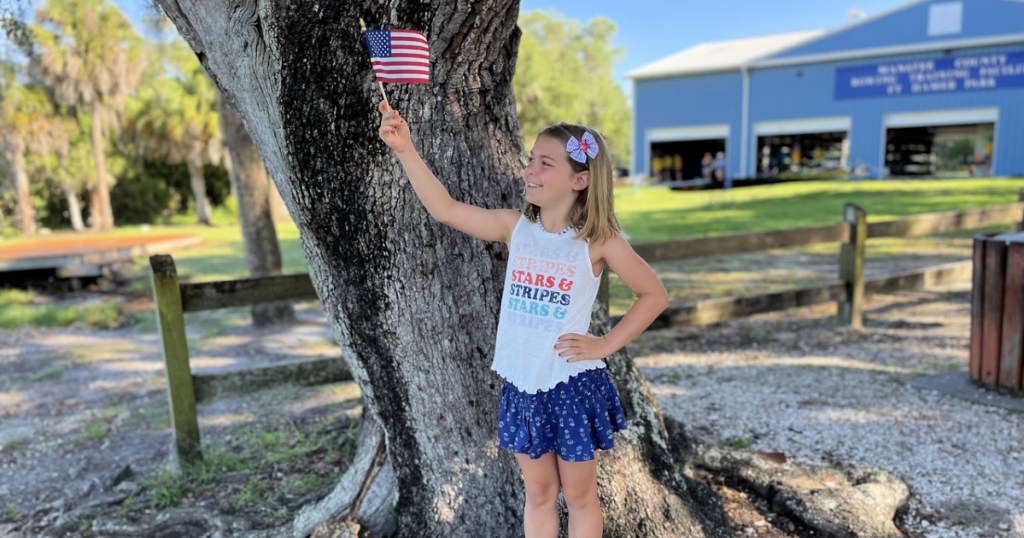 girl wearing patriotic clothing and holding american flag
