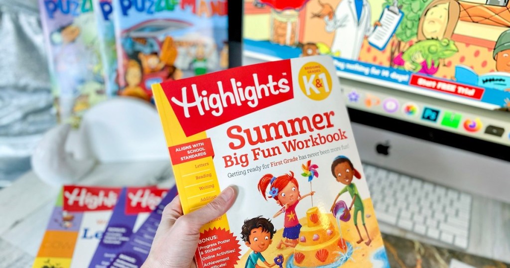 hand holding highlights magazine in front of computer