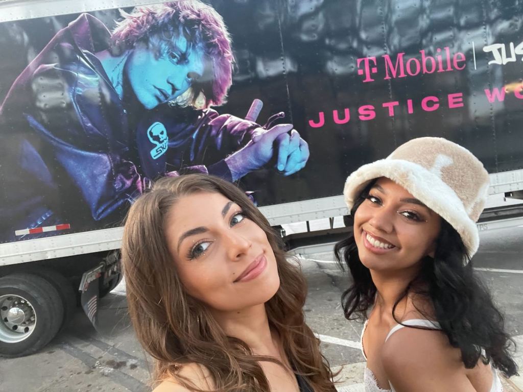 two woman posing in front of justin bieber concert truck outside