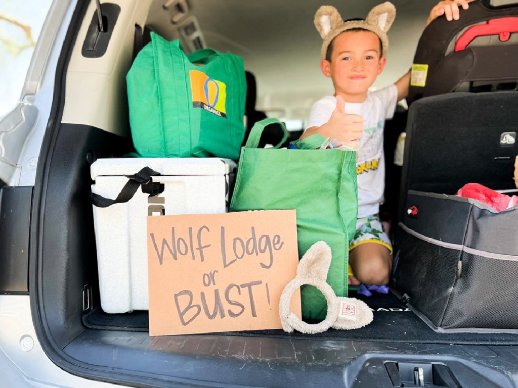 kid in car with wolf lodge or bust sign