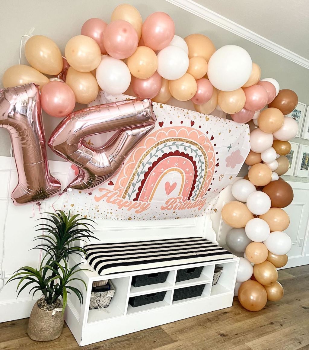 colorful peachy pink balloon arch and fourteen number birthday balloons