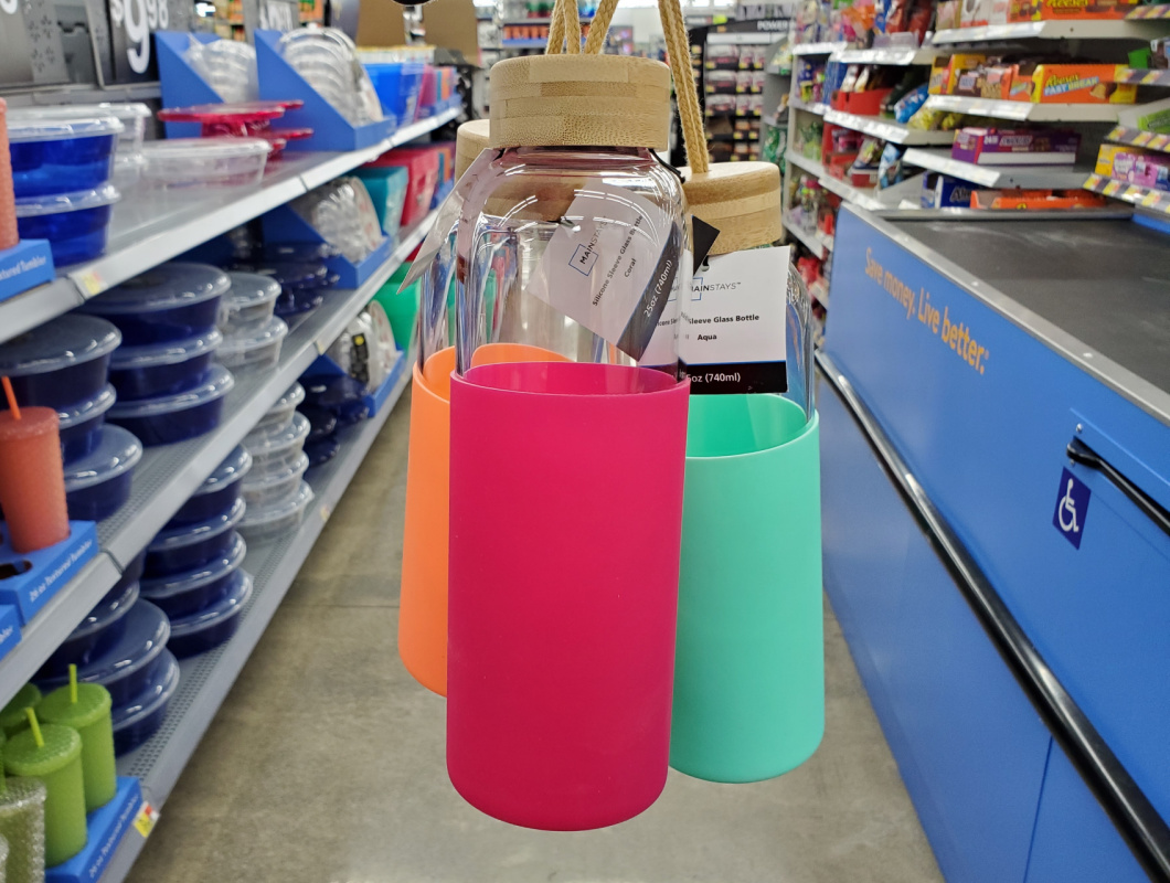 collection of glass water bottles being dangled from lids in a store aisle