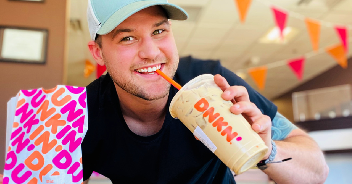 man holding a dunkin cup and bag