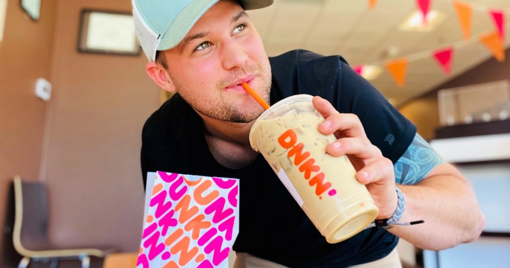 man holding ice coffee from dunkin