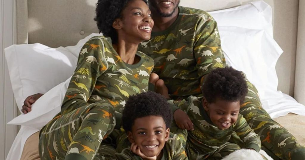 woman, man, and 2 boys laying in bed in matching dinosaur pajamas