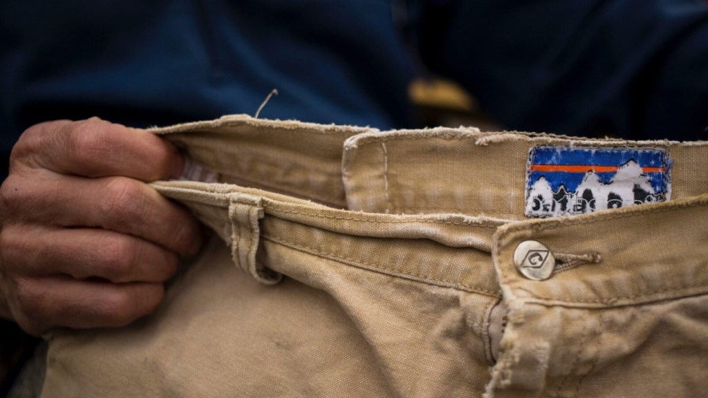 man holding waistband of worn Patagonia khakis