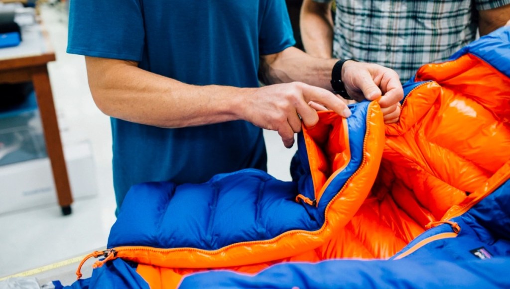 man fixing zipper on blue and orange jacket