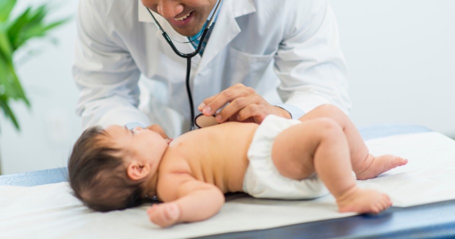 pediatrician listening to baby's heart on table