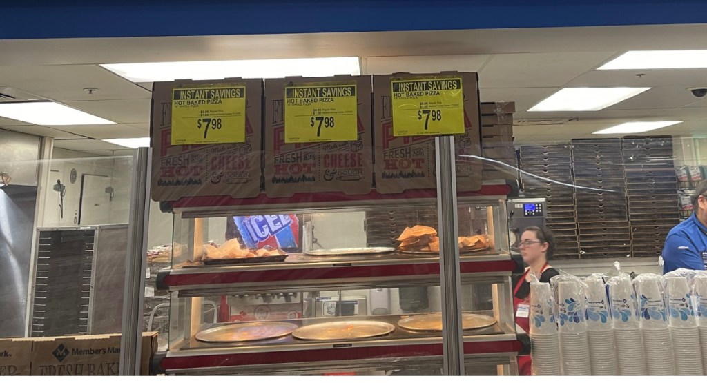 sams club cafe display with workers and pizza sign