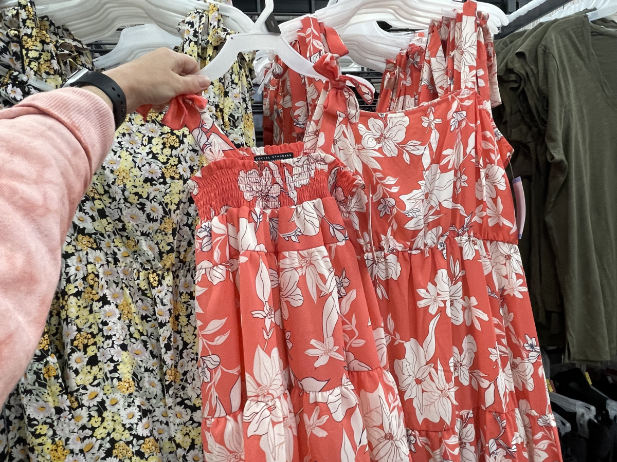 woman holding up a matching girls dress against the matching mommy dress in a store