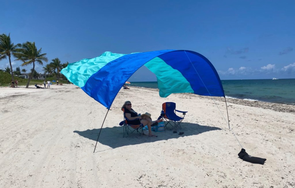 large blue and teal beach shade with woman sitting in beach chair