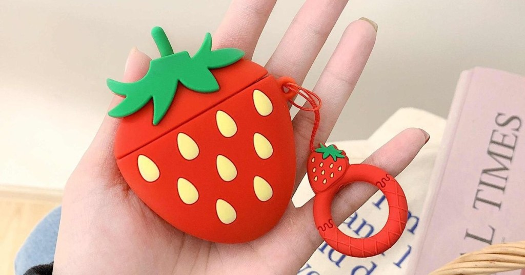 holding an AirPods case shaped like a strawberry