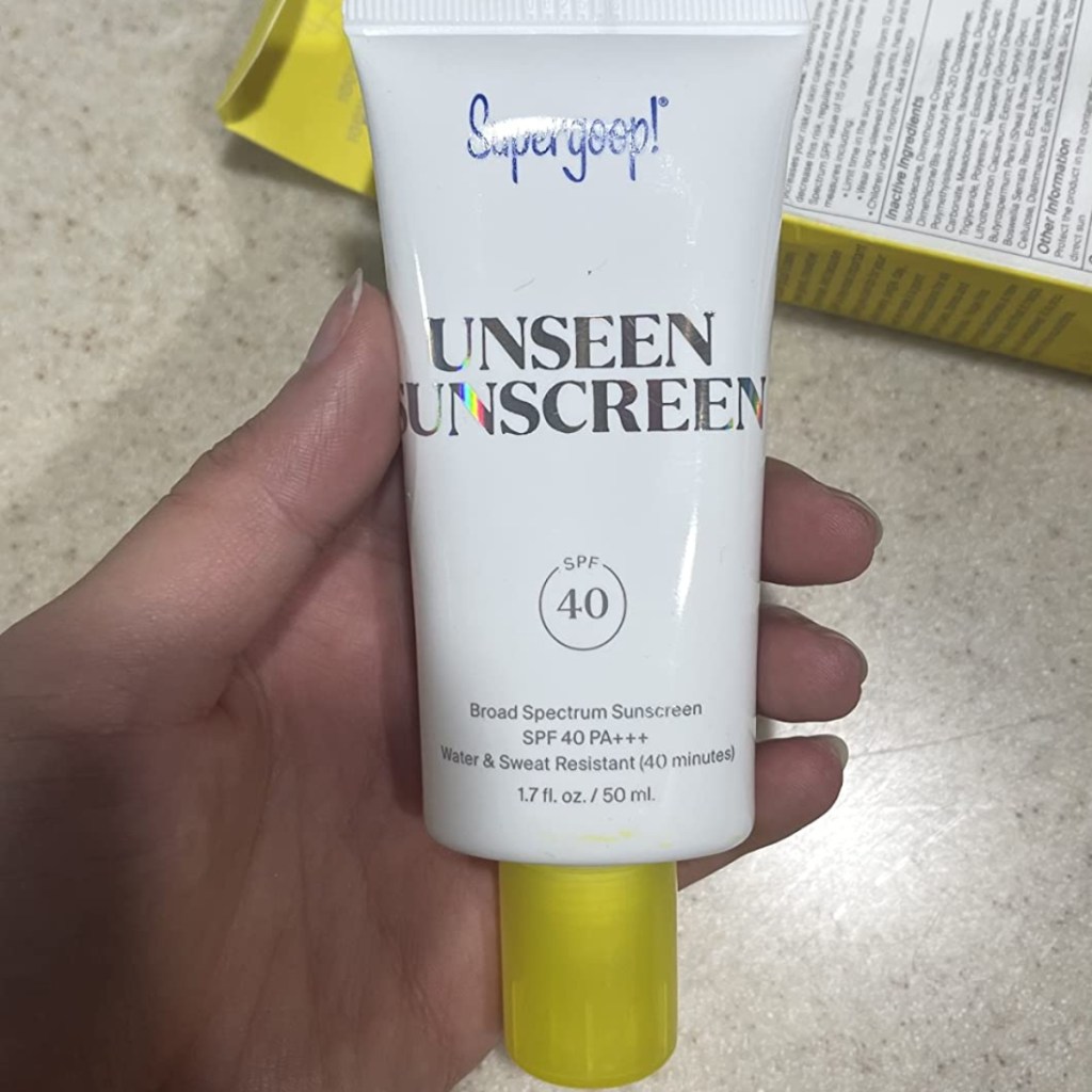 holding a tube of sunscreen
