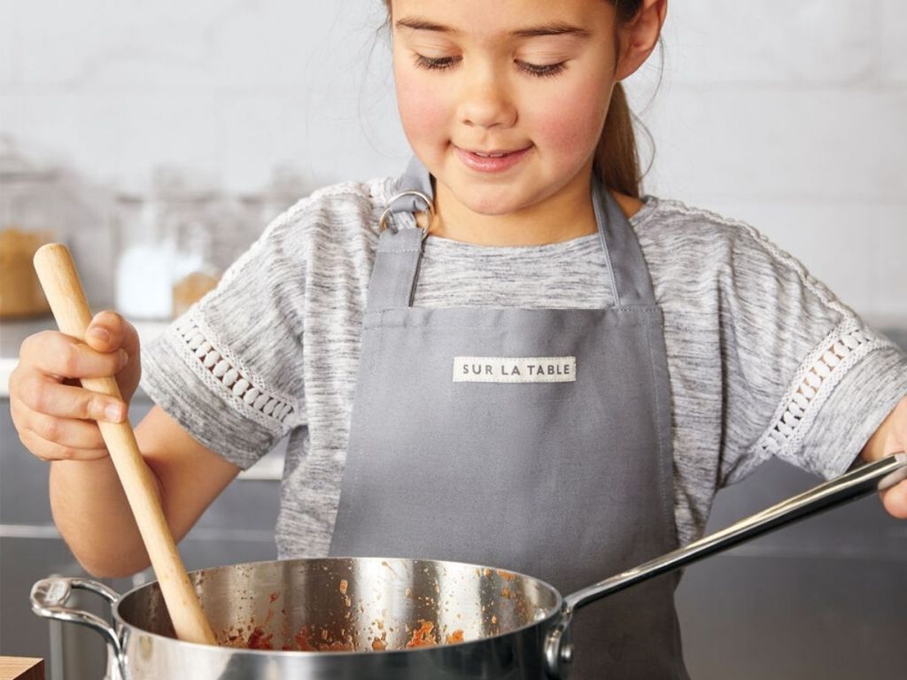 girl wearing Sur la table apron stirring pot