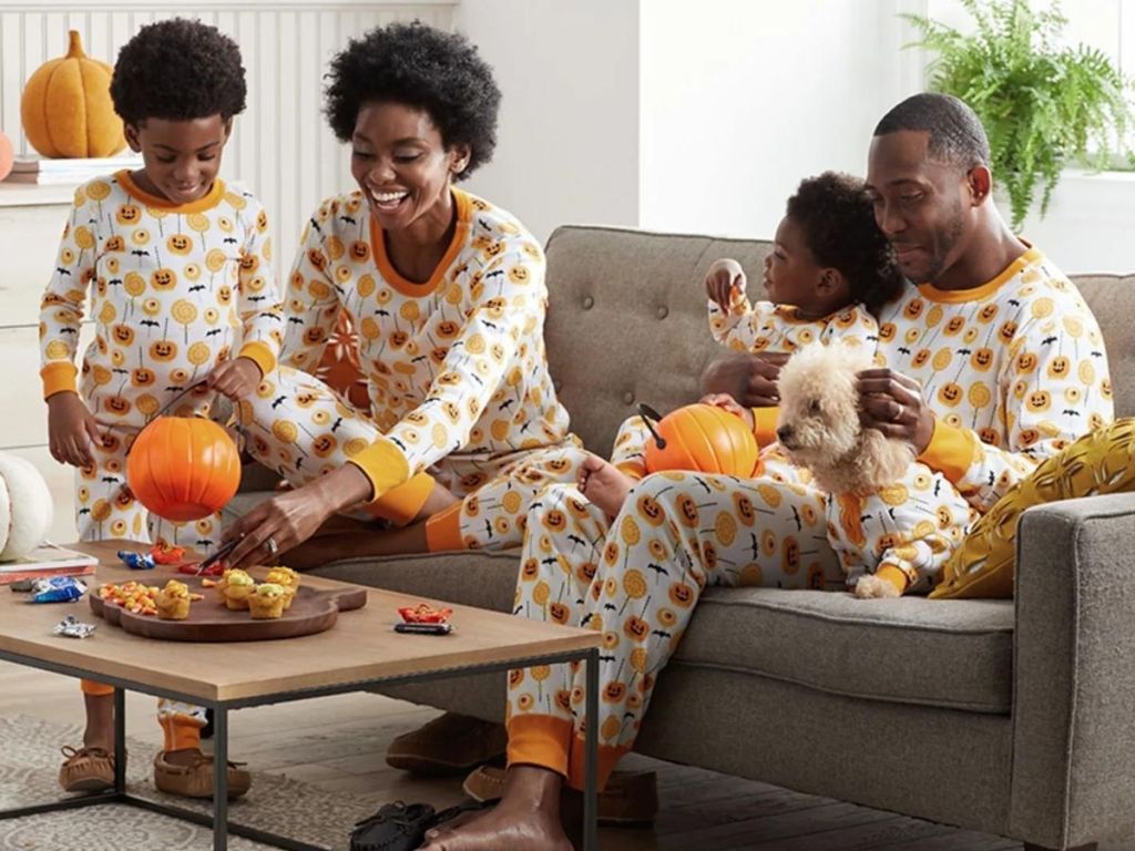 family wearing matching pumpkin pajamas sittingon the couch
