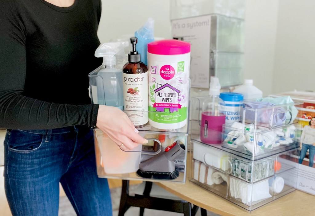 woman holding clear organizers with bath and kitchen cleaning the home edit products