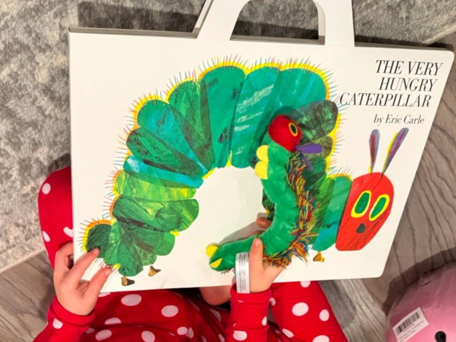 little girl playing with a Giant The Very Hungry Caterpillar board book and plush