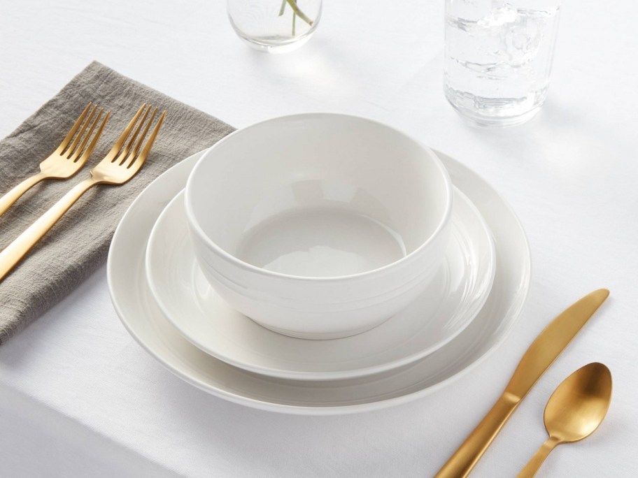 white threshold dining set surrounded by gold flatware