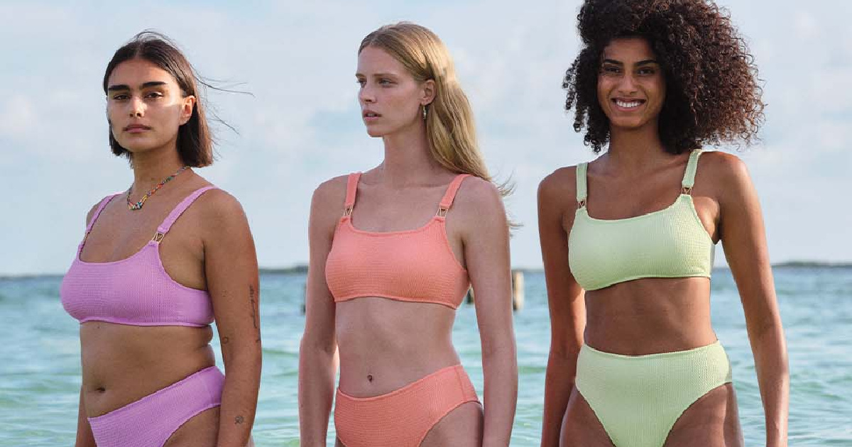 three women wearing swimwear separates standing in the ocean