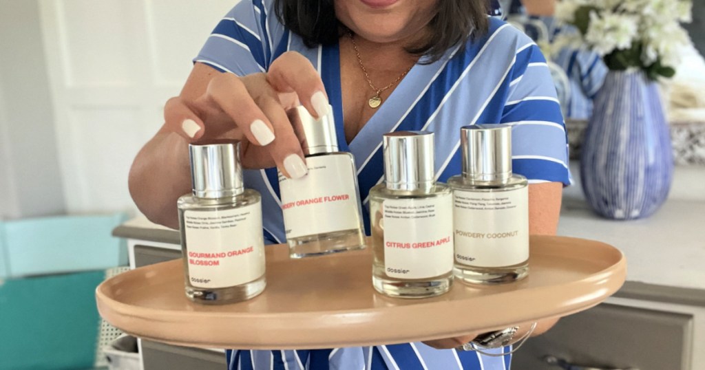 woman holding 4 dossier perfumes