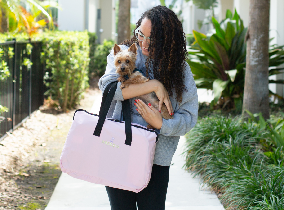 woman holding dog and pink carrying case