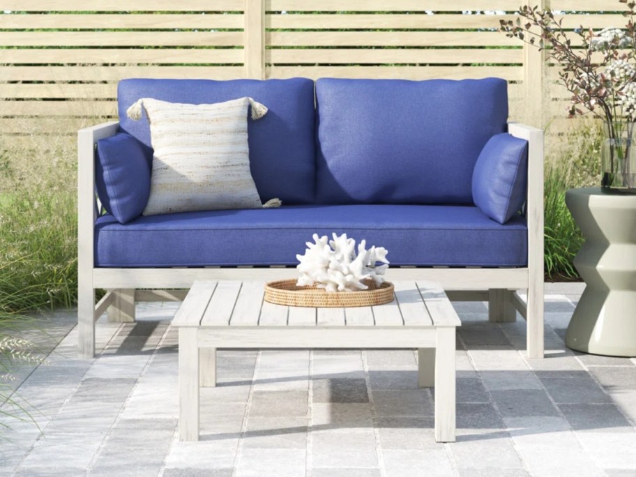 outdoor loveseat and coffee table set with blue cushions on a patio