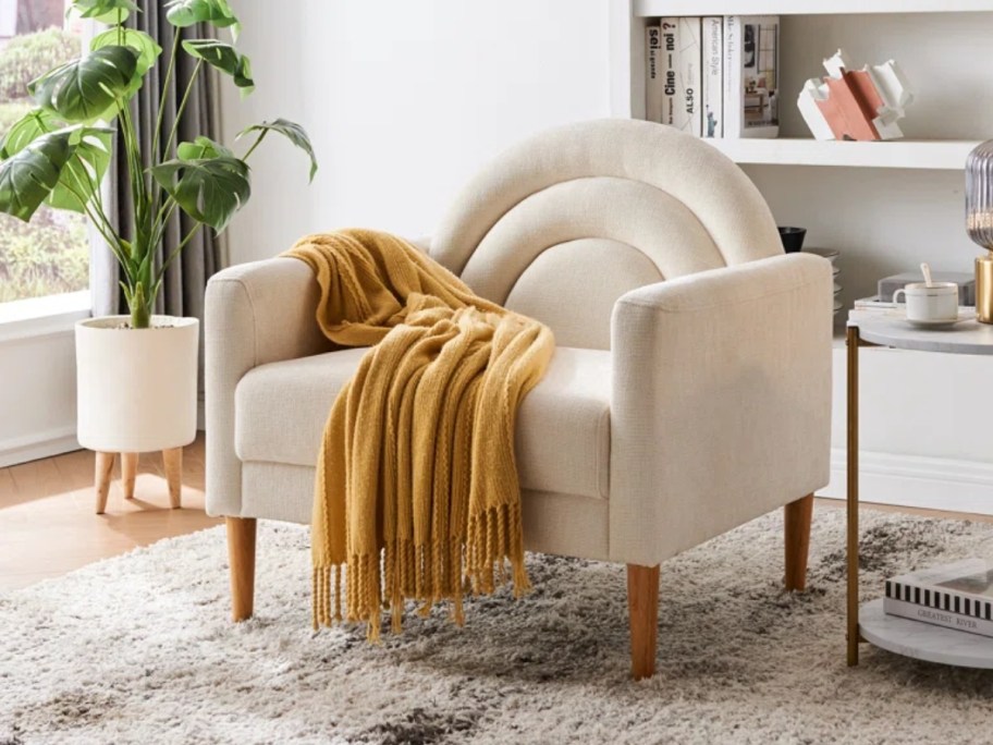 large off white modern style accent chair with a yellow throw blanket on it in a living room