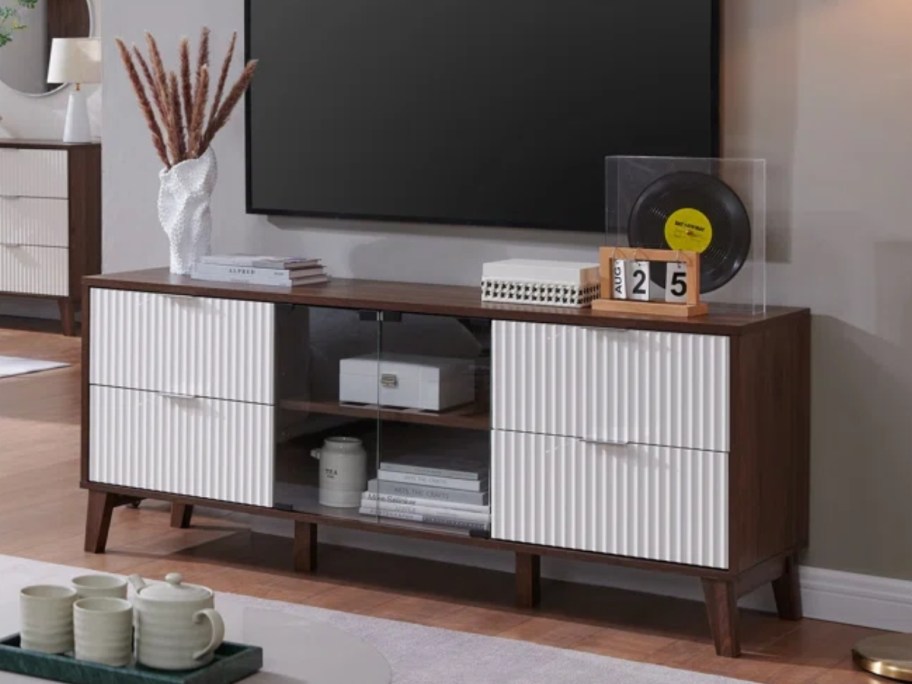 dark brown wood media console with white ridged doors and glass center doors with a TV and decor on top