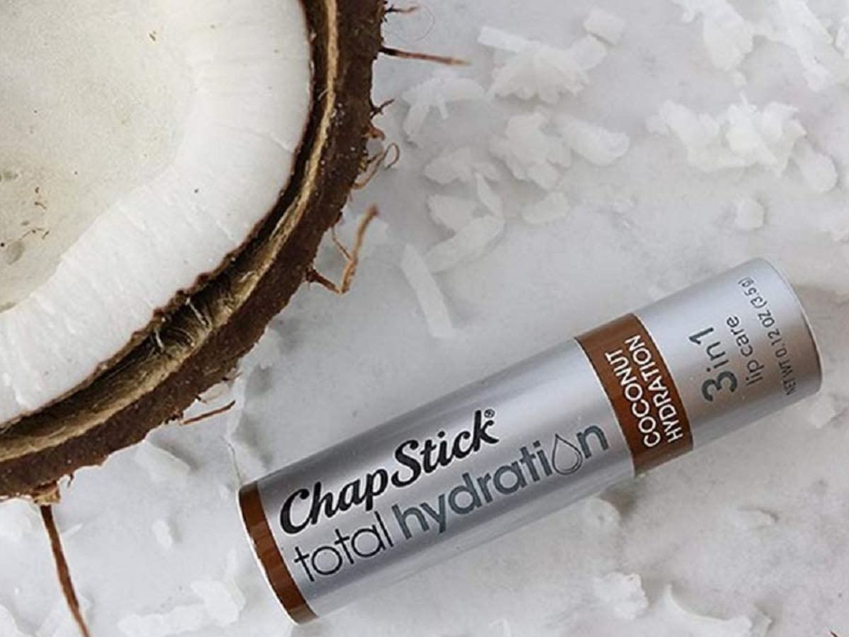 Chapstick Coconut Total Hydration next to a piece of coconut and some coconut shreds