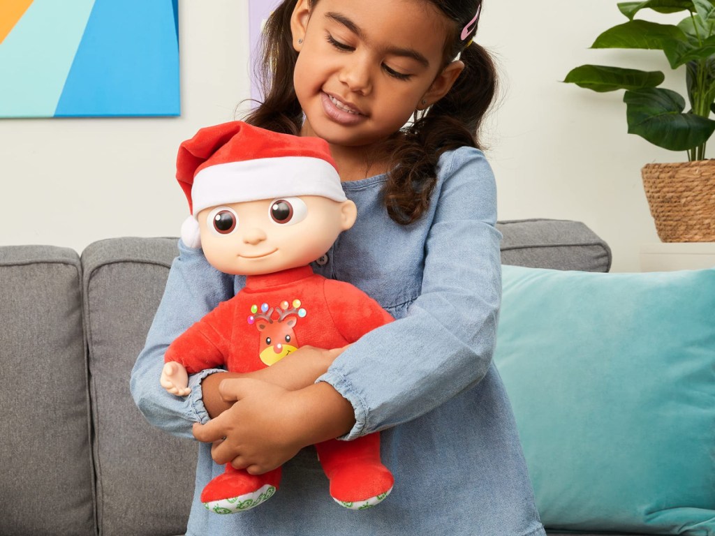 girl holding Cocomelon Christmas musical doll
