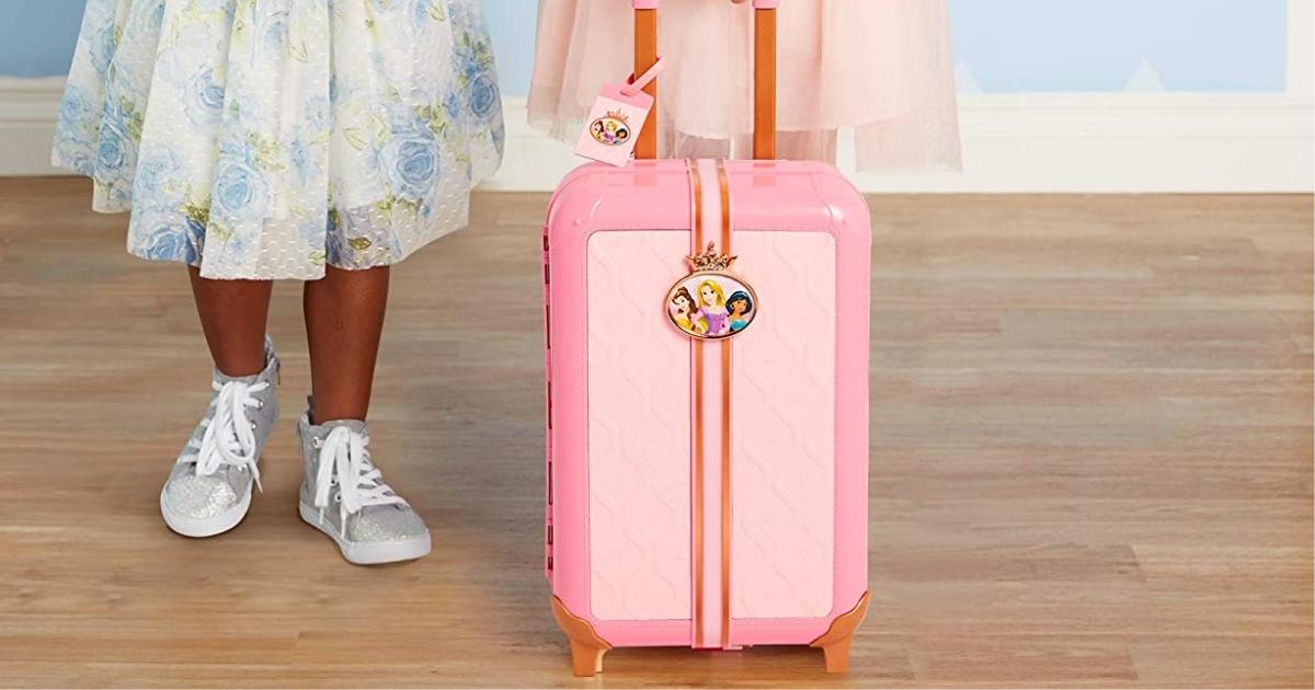 two girls wearing dresses and sneakers standing behind the Disney Princess Suitcase Playset