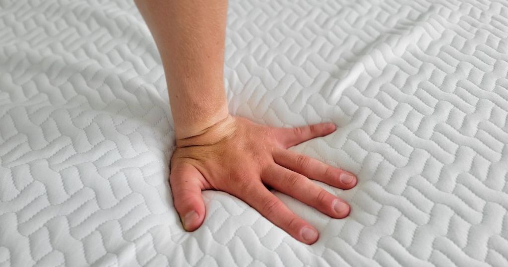 hand pushing down on mattress topper