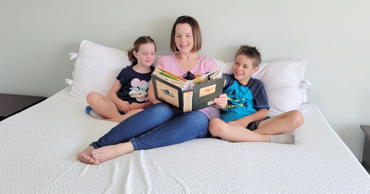 mom with children reading a storybook on a mattress cover 