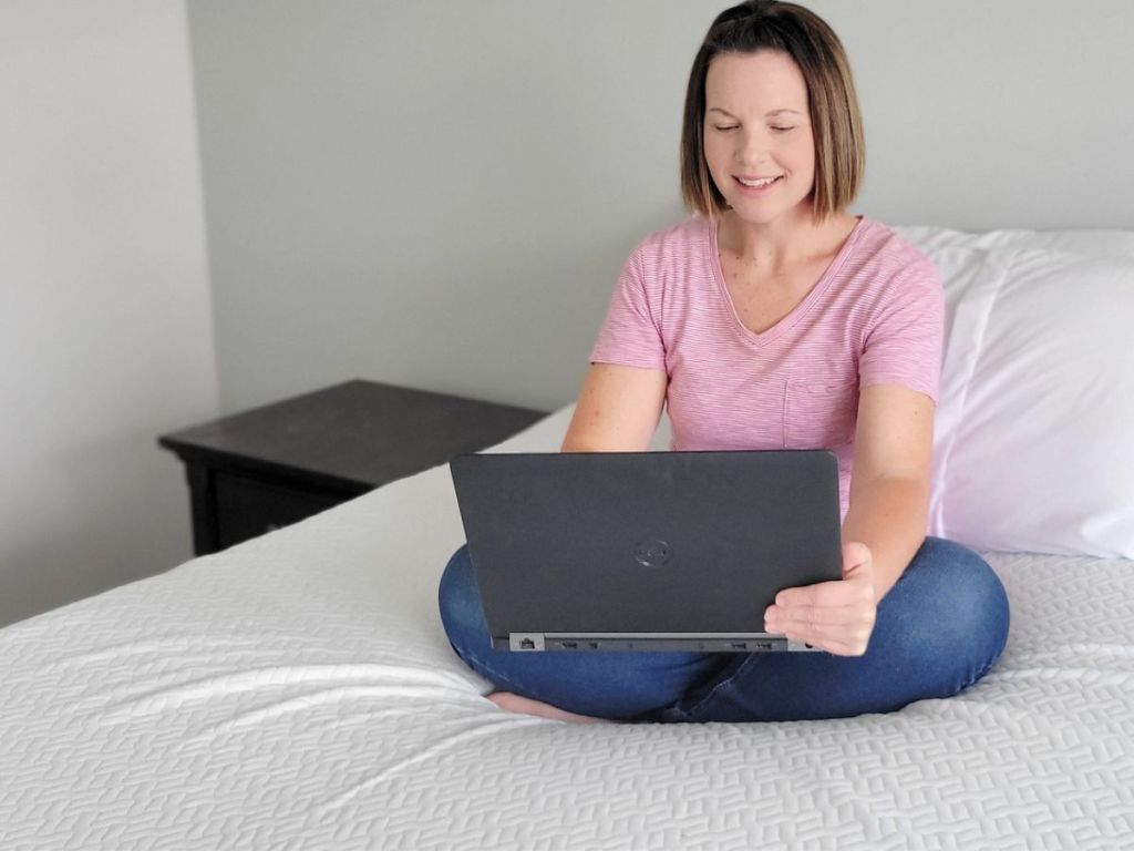 woman sitting on a Dreamsmith Memory Foam Topper using a laptop