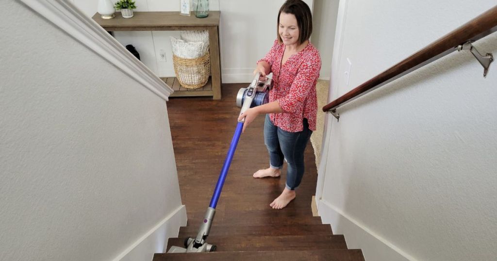 woman using cordless vacuum to clean stairs