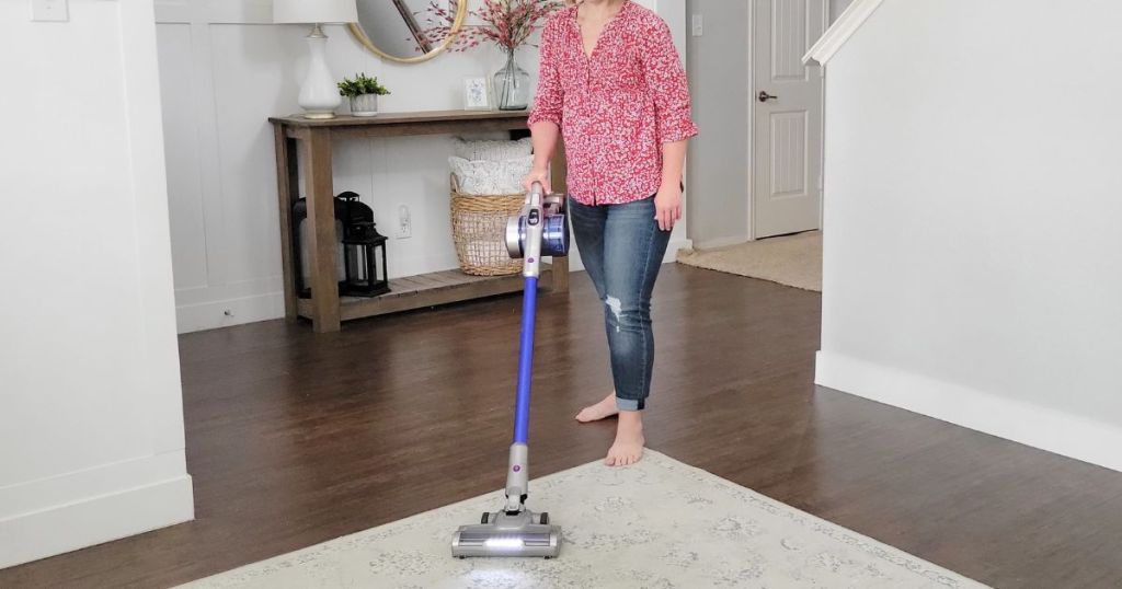 woman using cordless vacuum on area rug